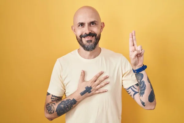 Hispanic Man Tattoos Standing Yellow Background Smiling Swearing Hand Chest — Stock Photo, Image