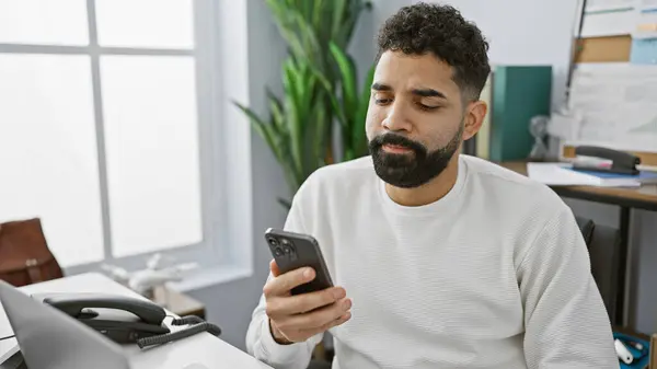 Focused Hispanic Man Using Smartphone Modern Office Setting Portraying Connectivity — Stock Photo, Image