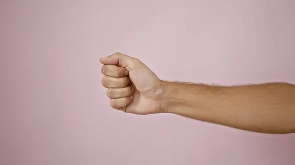 Close-up of a male fist against a pink isolated background, conveying strength or solidarity.