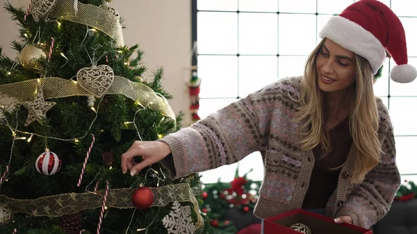 Genç sarışın kadın gülümsüyor evde kendine güvenen bir Noel ağacı süslüyordu.