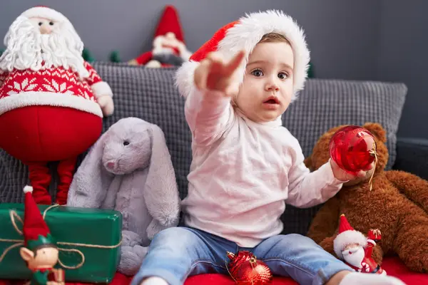 Suloinen Valkoihoinen Vauva Leikkii Joulukoristeita Pallo Istuu Sohvalla Kotona — kuvapankkivalokuva