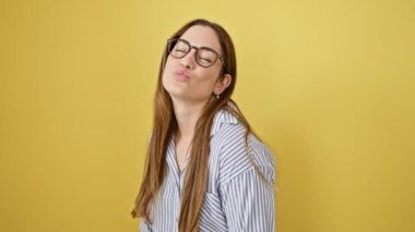 Mavi gözlü sevimli genç bir kadın, neşeli bir aşk öpücüğü veriyor, seksi ama sevimli görünüyor. Sarı izole edilmiş arka planda gözlük takan kendine güvenen sevimli kız..