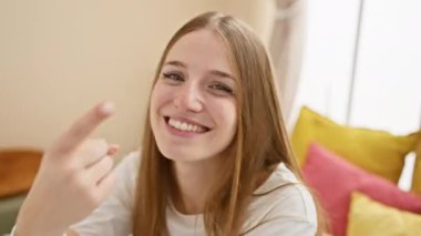 Parlak sarışın kadın, pijamalı, yatak odasında cilt bakımı rutini yapan, temiz, taze yüzünü gösteren, yatakta oturan, refah ve doğal güzellikle ışıldayan..