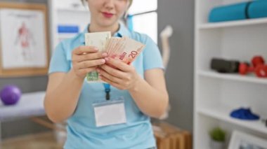 Klinikteki genç sarışın kadın içeride İsrail şekellerini sayıyor.