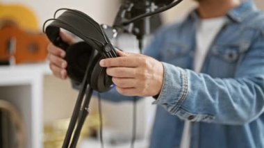 Kot ceketli İspanyol adam müzik stüdyosunda mikrofon ayarlıyor.