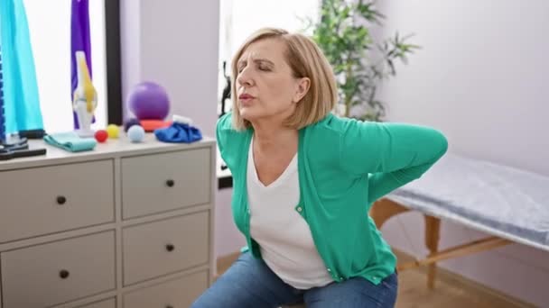Reife Kaukasische Frau Mit Schmerzen Einer Physiotherapie Klinik Drinnen Sitzend — Stockvideo
