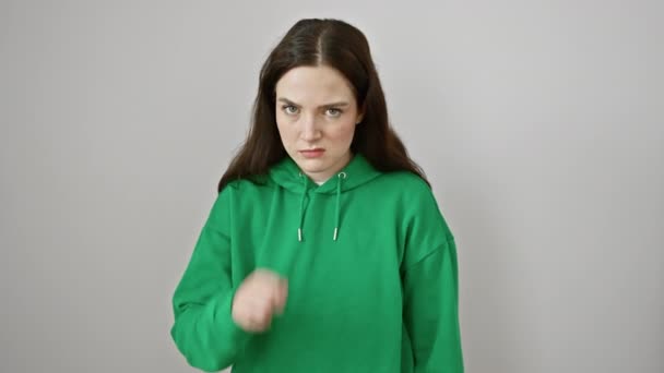 白い背景に隔離されたスウェットシャツの熱心な若い女性は 暴力的な侵略を示す脅迫的なナイフのジェスチャーとして手を切断します — ストック動画