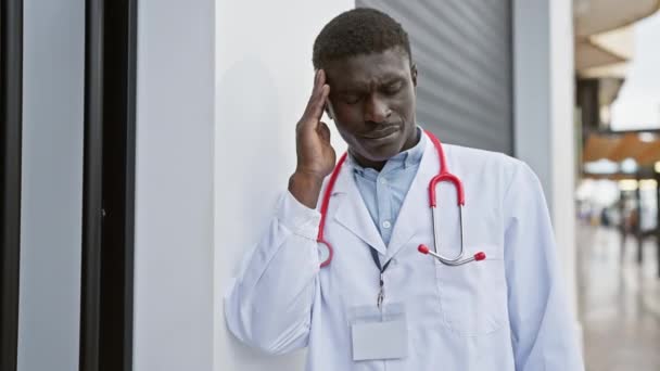 アフリカの男性医師は 都市病院の設定に立っている間にストレスを感じ 医療従事者の課題を紹介しています — ストック動画