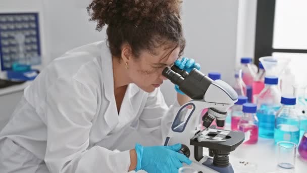 Científica Hispana Examinando Espécimen Con Microscopio Laboratorio Con Químicos Coloridos — Vídeo de stock