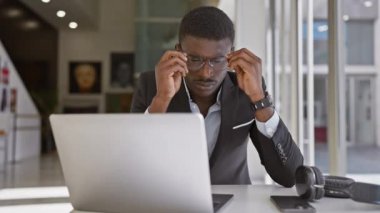 Modern ofis ortamında dizüstü bilgisayarla çalışan takım elbiseli Afrikalı iş adamı..