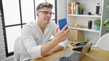 Yakışıklı, beyaz bir adam, ciddi bir iş adamı, kendini ofise kaptırmış, bilgisayarına mesaj yazarken çok çalışıyor, bir iş fikrinden şüphe ediyor, akıllı telefon ekranına bakıyor.