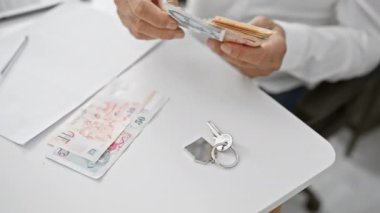 Bir ofis ortamında tek başına dolar sayan orta yaşlı bir adam, finans, iş ve döviz kuru faaliyetlerini gösteriyor..