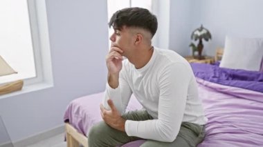 Genç İspanyol adam pijama giyip yatağa uzanmış başarılı bir fikri işaret ediyor. Heyecanlı ve mutlu. Bir numara. yatak odasında