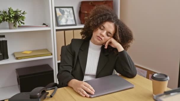 屋内環境でラップトップの前に オフィスデスクで疲れたり退屈を感じるカーリーヘアのヒスパニック女性 — ストック動画
