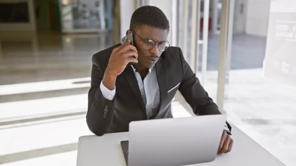 수트를 아프리카 남자는 전화로 말하는 사무실에서 노트북에서 일합니다 — 비디오