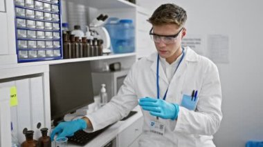 Ciddi, sakallı, beyaz bilim adamı yüksek teknoloji laboratuarında test tüpüne örnek dolduruyor ve güçlü mikroskoba bakıyor.