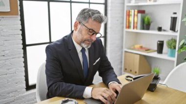 Genç, beyaz saçlı, stresli, ofiste iş stresi çekerken gözlük takan yakışıklı, ev içi iş problemleriyle boğuşan İspanyol bir adam.