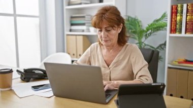 Mest olmuş orta yaşlı bir ofis kadını dizüstü bilgisayarıyla oturuyor, kollarını başarıyla kaldırmış, neşeli zaferinin tadını çıkarıyor.