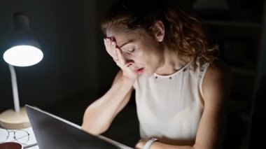 Ofiste geç saatlere kadar çalışan stresli bir kadın dizüstü bilgisayarının önünde masa lambasının altında bitkin hissediyordu..