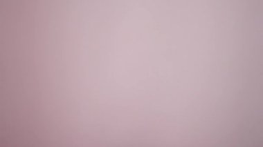 İzole edilmiş pembe arka plana karşı kredi kartı tutarak el çabukluğu