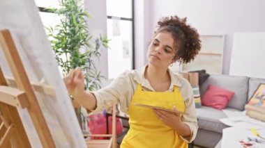 Güçlü İspanyol kadın sanatçı, kıvırcık saçlı. Stüdyoda kaslarını kasıyor. Güç ve güzellik gösterisi yapıyor.