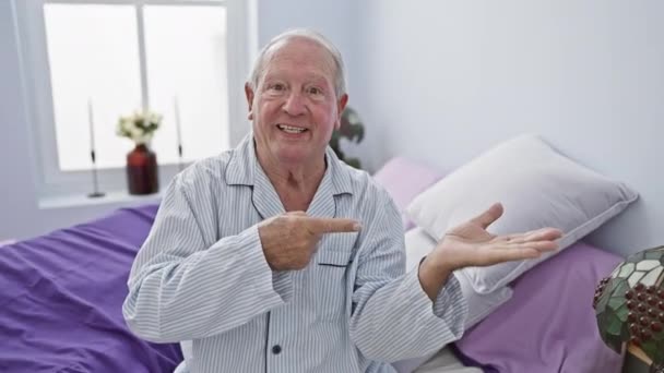 Веселый Пожилой Человек Изумленный Сидя Кровати Пижаме Уверенно Представляя Рукой — стоковое видео