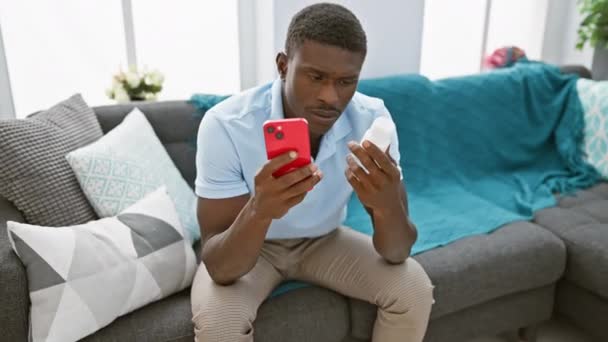 Afrykanin Bada Leki Podczas Korzystania Smartfona Nowoczesnym Salonie — Wideo stockowe
