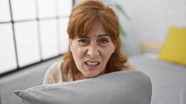 Medelålders Kvinna Som Kramar Kudde Sovrummet Sitter Sängen Med Förbryllat — Stockvideo