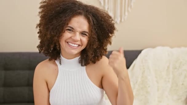 Веселая Латиноамериканка Вьющимися Волосами Счастливо Указывающая Сторону Сидя Своем Домашнем — стоковое видео