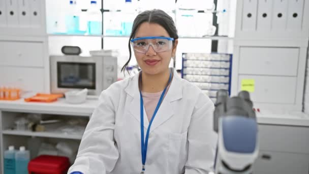 陽気な若いヒスパニックの科学者が研究室で優れたサインを点滅 大きい笑顔および涼しい安全ガラスが付いている成功を表現する豪華で 自信がある女性 — ストック動画