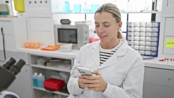 一位面带微笑的女科学家在实验室使用智能手机 唤起了专业精神和现代技术 — 图库视频影像