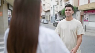 Bir kadın ve bir erkek, bir şehir arkaplanına karşı sevgi ve beraberlik anlarını iletirken, bir şehir caddesinde sevgiyle kucaklaşırlar..