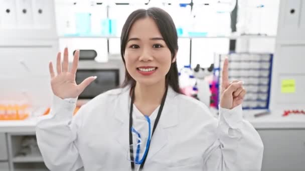 Neşeli Genç Çinli Bilim Kadını Laboratuvarda Gülümseyerek Altı Numarayı Gösteriyor — Stok video