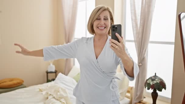 一位快乐的中年妇女穿着睡衣跳舞 在明亮的卧室里自言自语 — 图库视频影像