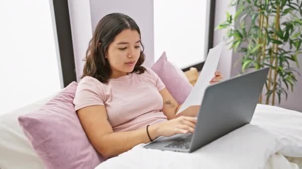 一个专心致志的惊慌失措的女人在舒适的卧室里的笔记本电脑上工作 手里拿着文件 在工作效率和舒适感之间保持平衡 — 图库视频影像