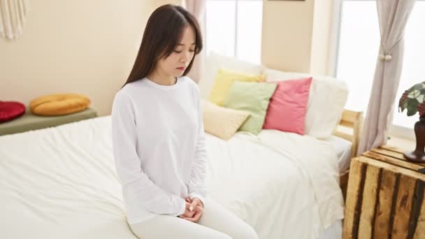 Una Joven Mujer Asiática Contemplativa Sienta Serenamente Una Cama Dormitorio — Vídeos de Stock