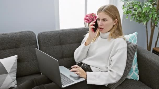 Mulher Loira Conversa Telefone Enquanto Usa Laptop Sofá Cinza Dentro — Vídeo de Stock