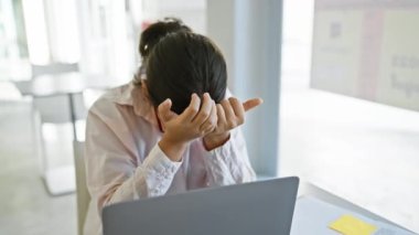 Ofiste gözlüklü stresli İspanyol kadın kendini işinden bunalmış hissediyor, dizüstü bilgisayarının başında..