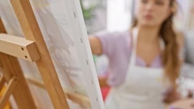 Yetenekli genç İspanyol kadın sanatçı, sanat stüdyosunda tutkuyla çizim yapıyor, yaratıcılık dünyasına dalmış, tuvalde boya fırçasıyla resim yapıyor, kapalı alanda sanat sınıfının ortasında ışıl ışıl bir güzellik..