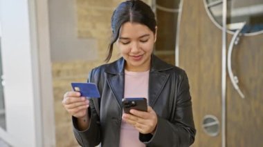 İspanyol kadın, şehir sokaklarında kredi kartı ve akıllı telefonu kontrol ediyor..