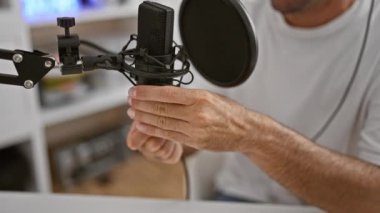 Çekici genç İspanyol erkek yayıncı, radyo stüdyosunda etkileyici bir şekilde konuşuyor.