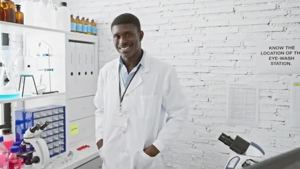 Ένας Χαμογελαστός Αφρικανός Λευκή Ρόμπα Στέκεται Ένα Καθαρό Λευκό Εργαστήριο — Αρχείο Βίντεο