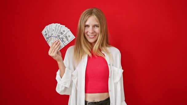 Blonde Frau Hält Fröhlich Geld Vor Rotem Hintergrund — Stockvideo