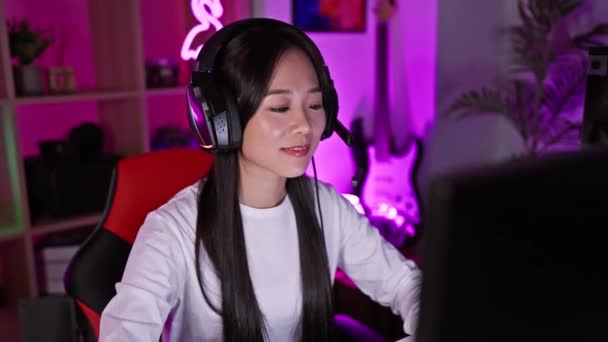 Lächelnde Asiatin Mit Kopfhörern Neonbeleuchtetem Spielzimmer Winkt Dem Computerbildschirm — Stockvideo