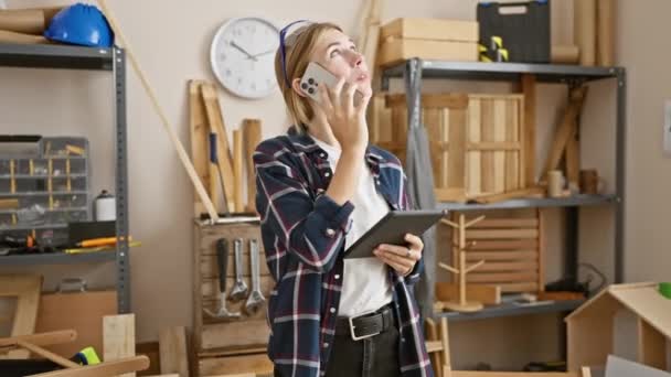 Blonde Woman Carpentry Workshop Talks Phone While Holding Tablet Surrounded — Stock Video
