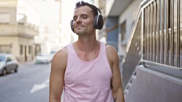 Kulaklıklı Mutlu Adam Güneşli Bir Şehir Sokağında Müzik Dinliyor — Stok video