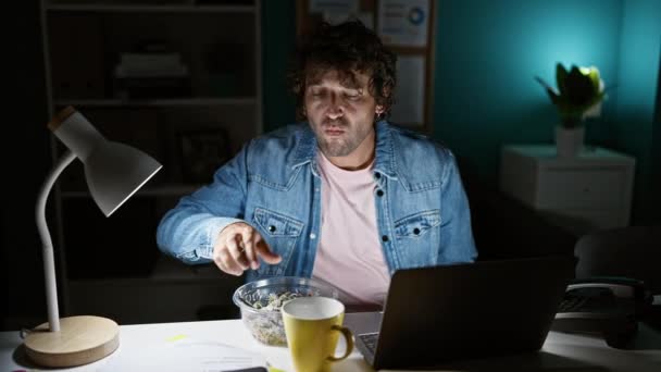 피곤한 남자는 자신의 사무실 책상에서 실내에서 램프에 커피를 마시고 노트북을 — 비디오