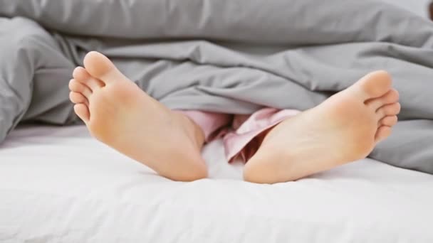 在室内舒适的床上 一个无名人士赤脚从被子下面伸出来的特写镜头 — 图库视频影像