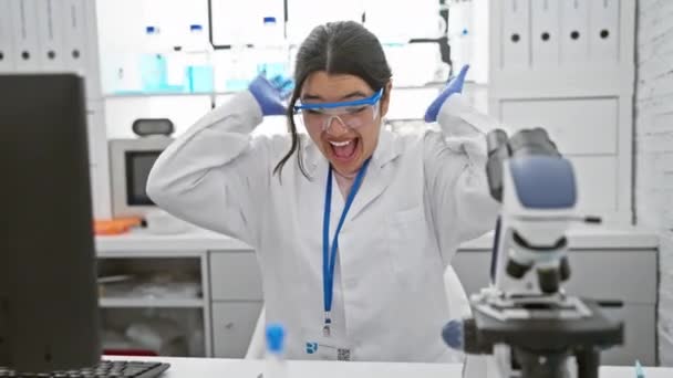 自豪的年轻女科学家戴着安全眼镜 带着喜悦的胜利之舞和喜悦的微笑在实验室庆祝胜利 — 图库视频影像