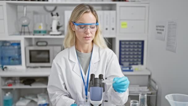 一位专注的金发女科学家在现代实验室使用显微镜 — 图库视频影像